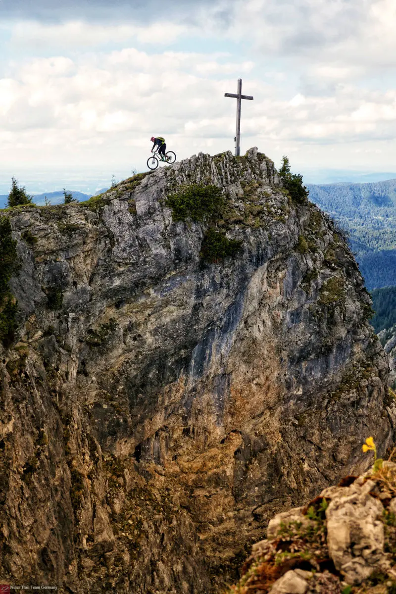 Gipfelkreuz mit Bike, Gratwanderung mit dem Bike am Abgrund.